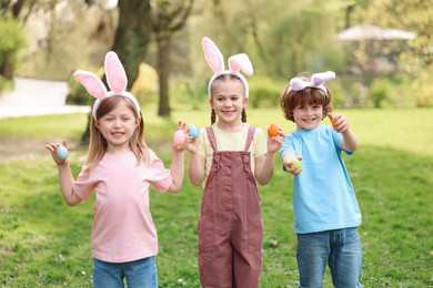 Easter celebration. Cute little children in bunny ears holding painted eggs outdoors