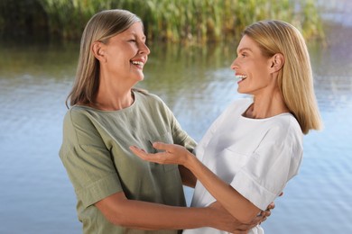 Photo of Family portrait of happy mother and daughter hugging near pond