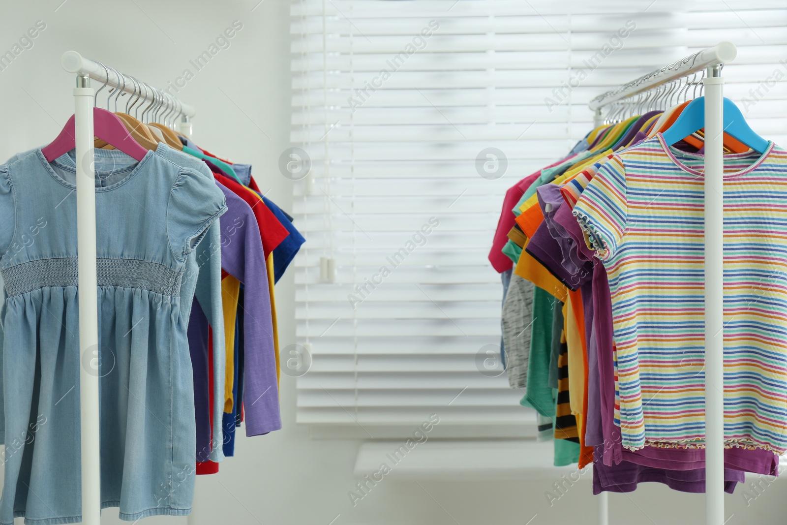 Photo of Different child's clothes hanging on racks indoors