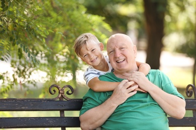 Photo of Elderly man with grandson on bench in park