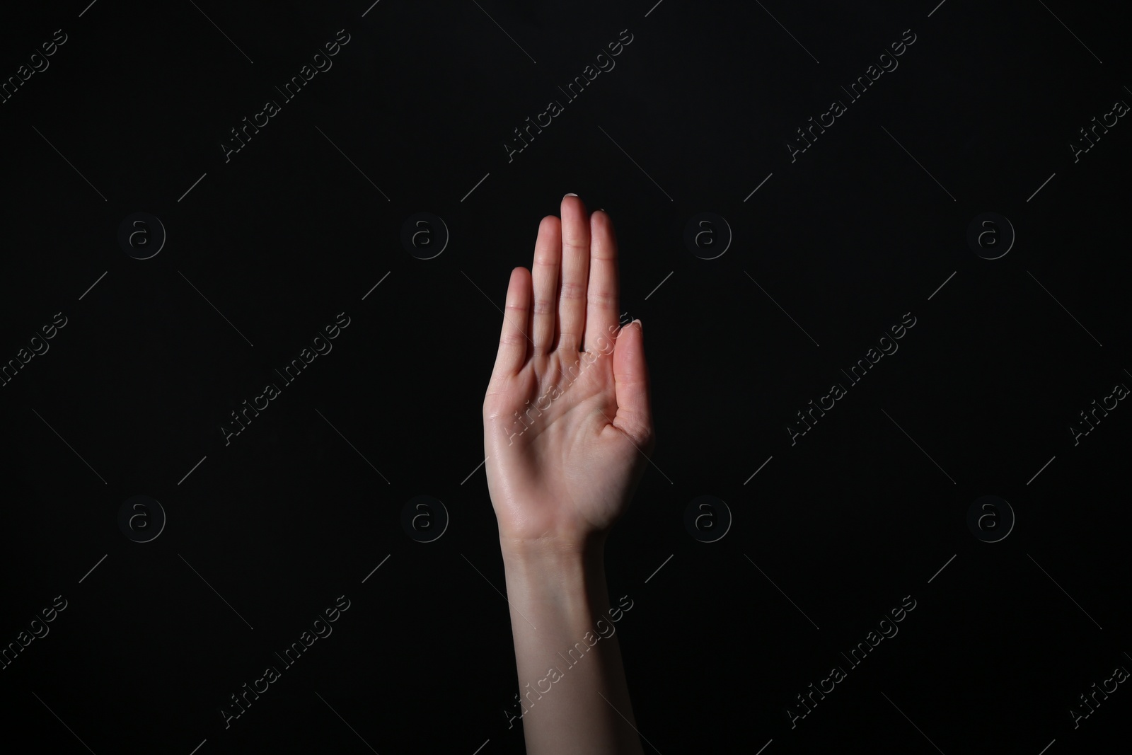 Photo of Woman showing open palm on black background, closeup