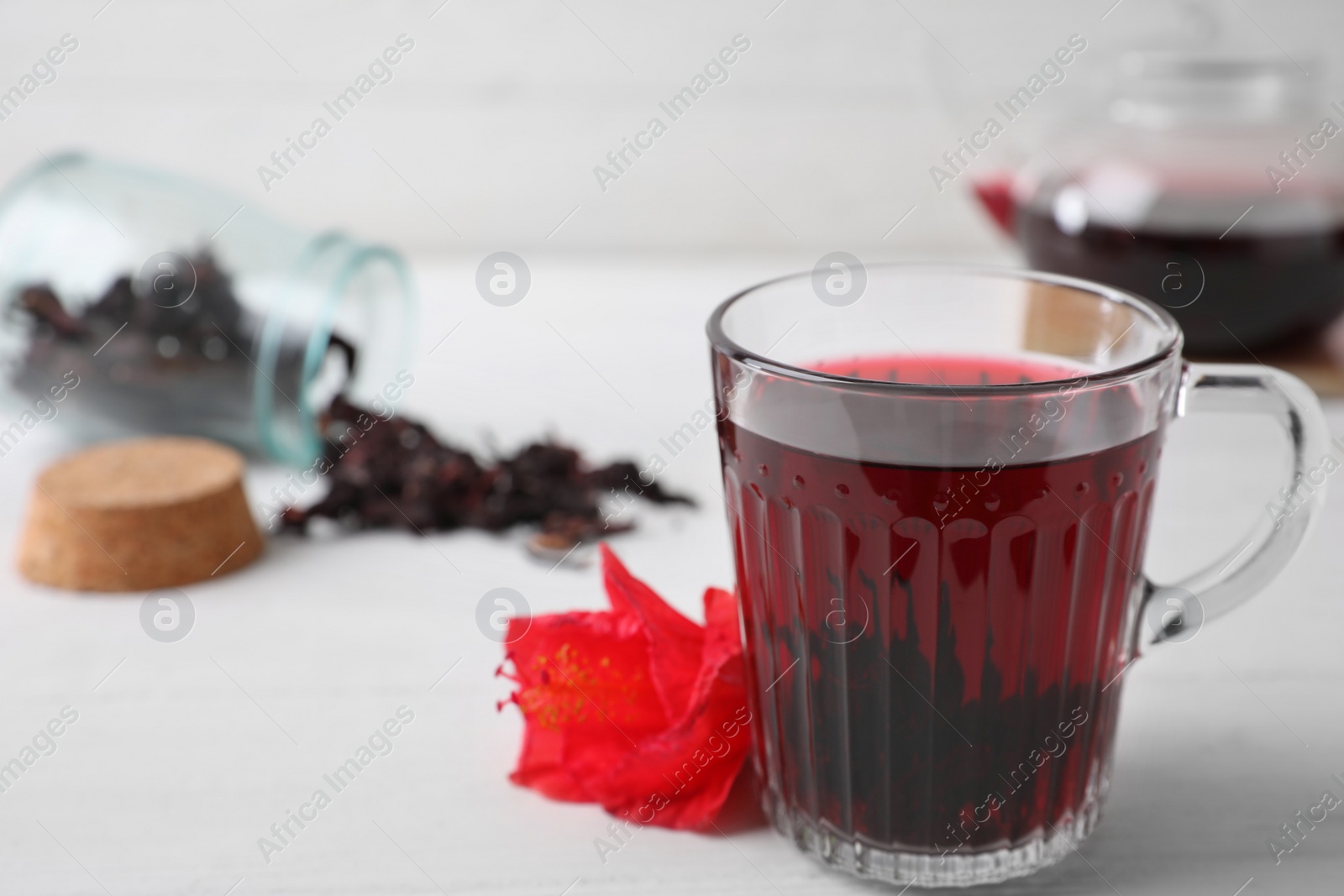 Photo of Delicious hibiscus tea and flower on white wooden table. Space for text