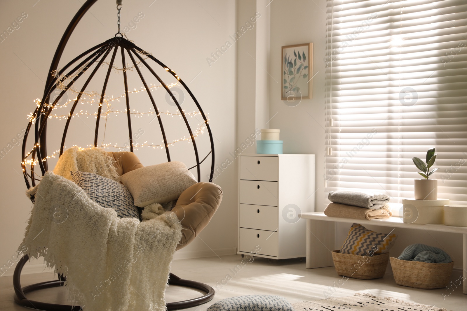 Photo of Cozy hanging chair with fairy lights in modern living room. Interior design