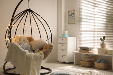 Photo of Cozy hanging chair with fairy lights in modern living room. Interior design