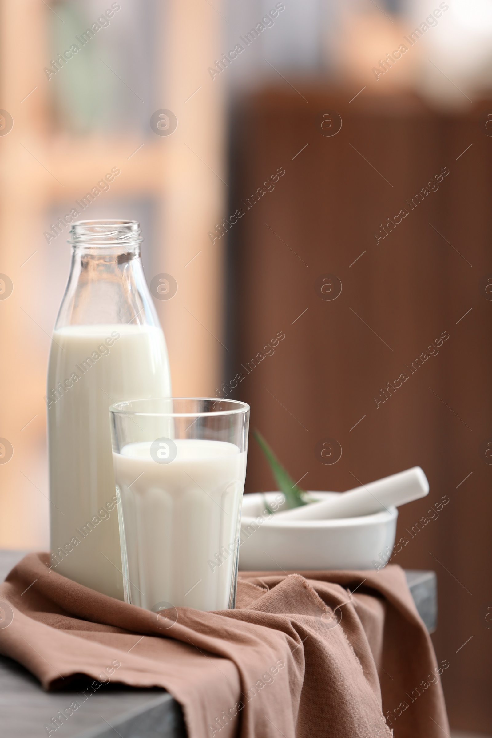 Photo of Glass and bottle with hemp milk on table against blurred background