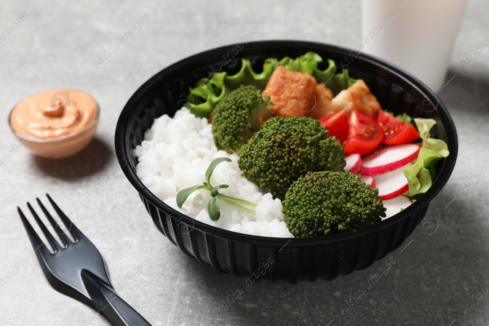 Photo of Healthy takeaway meal in plastic bowl on light grey table