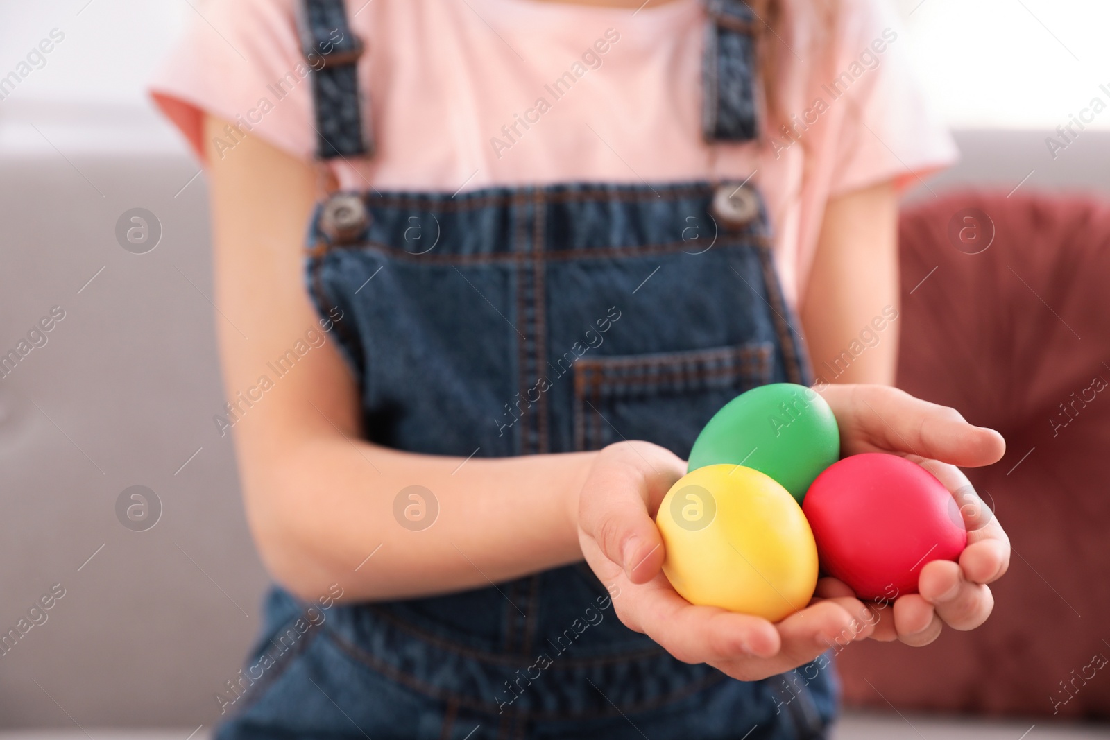 Photo of Little girl holding Easter eggs indoors, closeup. Space for text