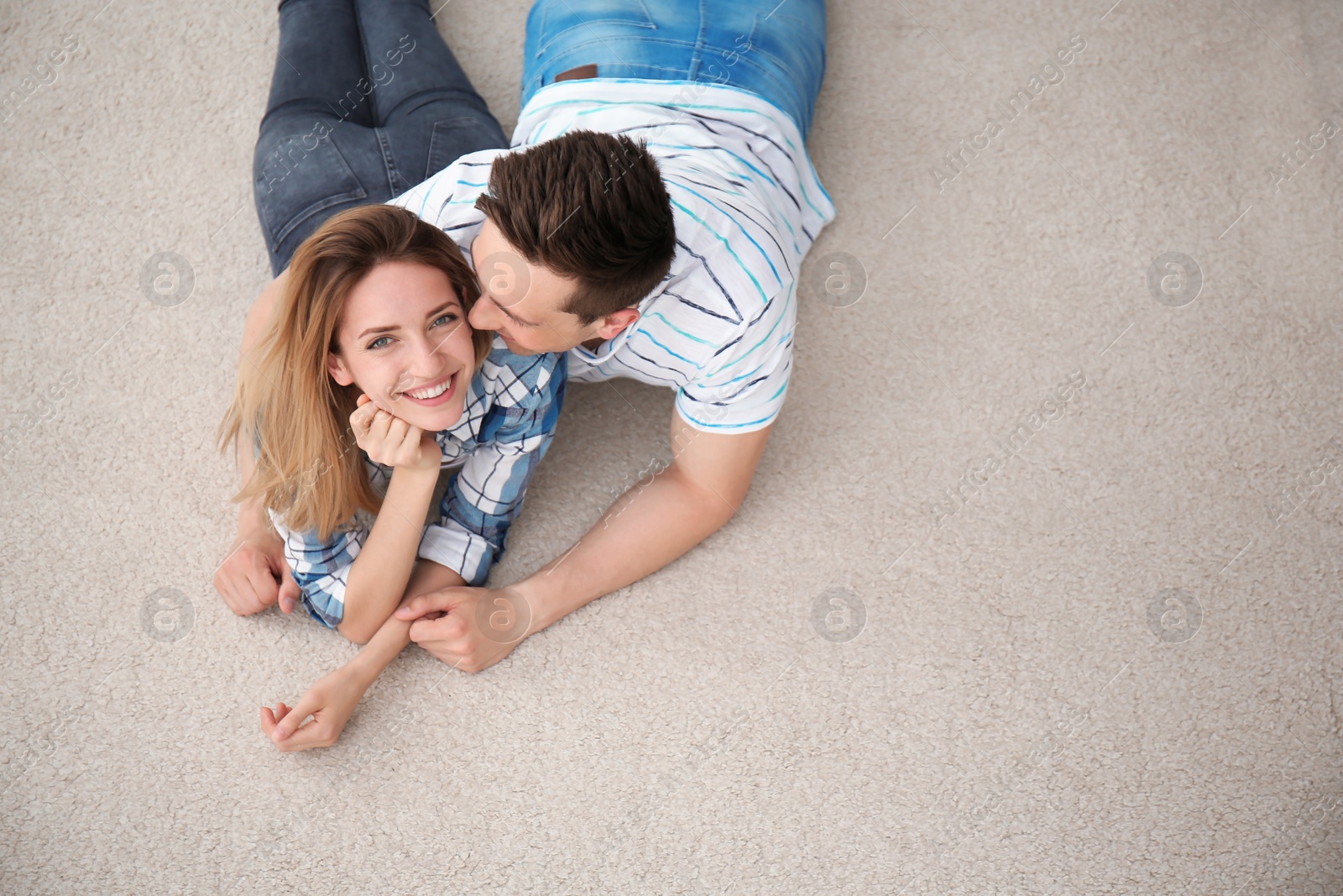 Photo of Lovely young couple lying on cozy carpet at home