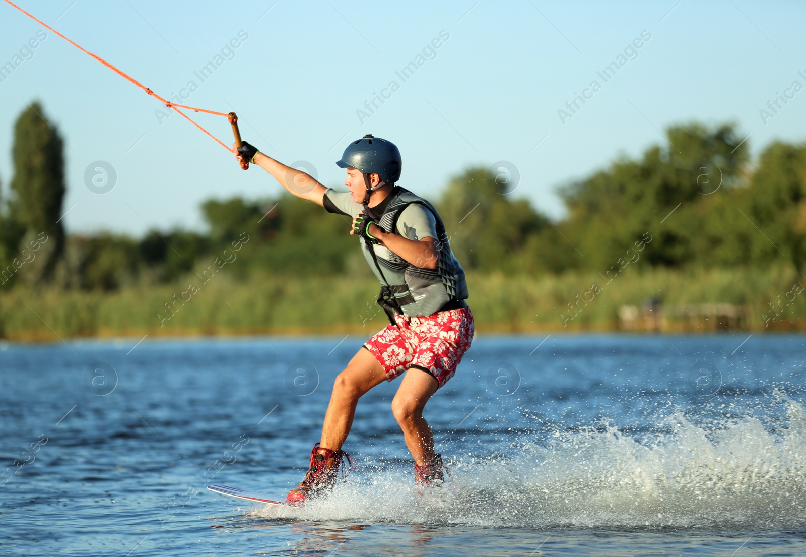 Photo of Teenage boy wakeboarding on river. Extreme water sport