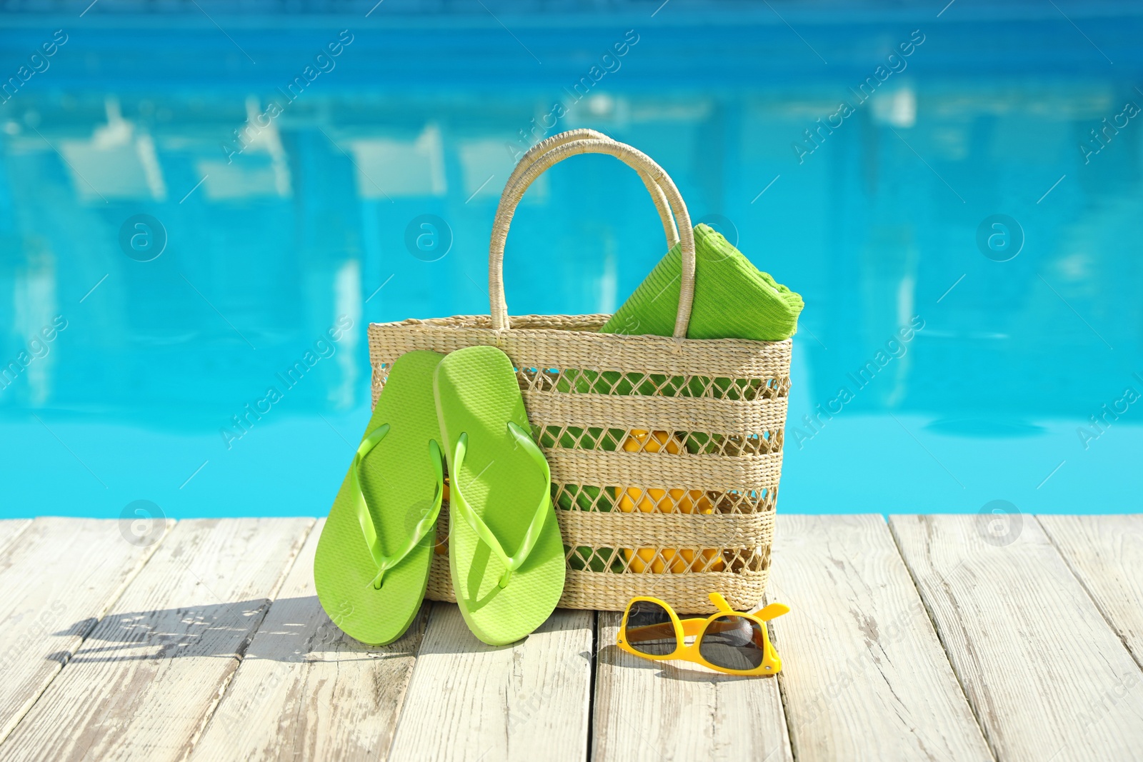 Photo of Beach accessories on wooden deck near outdoor swimming pool