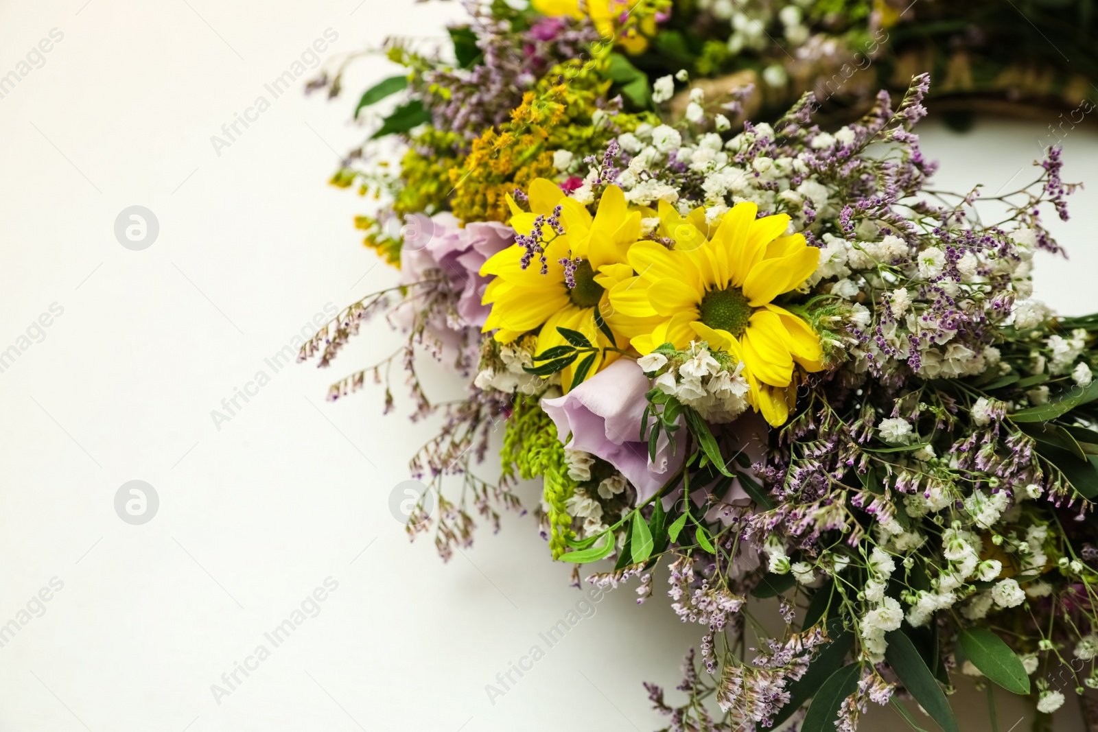 Photo of Wreath made of beautiful flowers on white background, closeup. Space for text