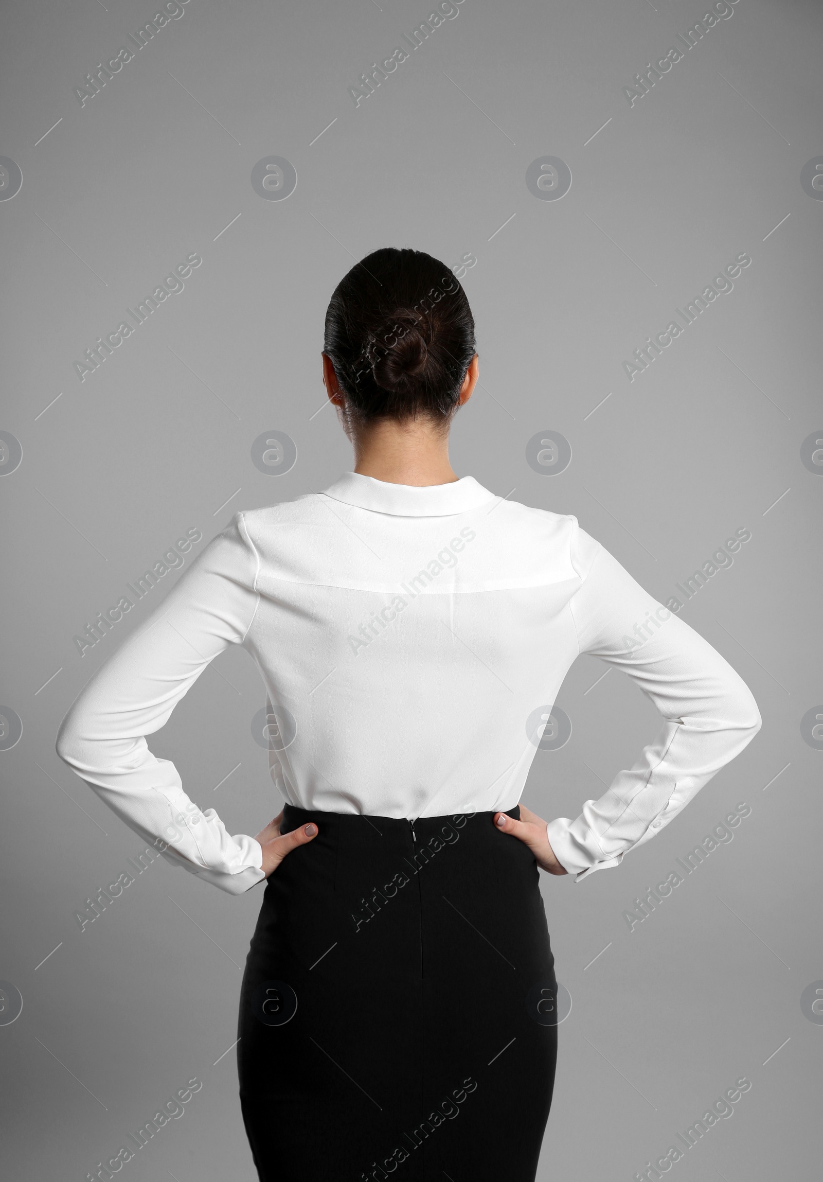 Photo of Young businesswoman in elegant suit on grey background, back view