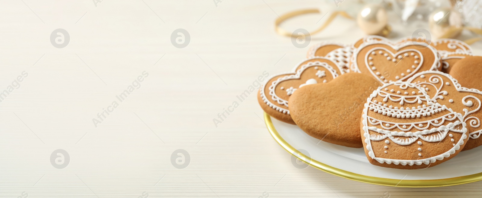 Image of Tasty heart shaped gingerbread cookies on white wooden table, space for text. Banner design
