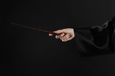 Photo of Wizard holding magic wand on black background, closeup