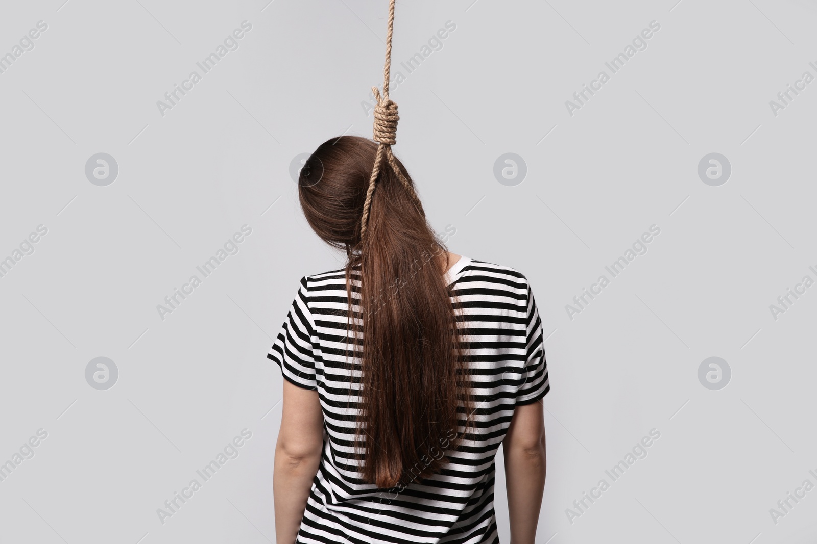 Photo of Woman with rope noose on neck against light grey background, back view