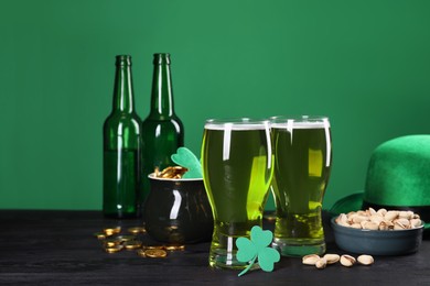 Photo of St. Patrick's day party. Green beer, leprechaun hat, pot of gold, pistachios and decorative clover leaf on wooden table