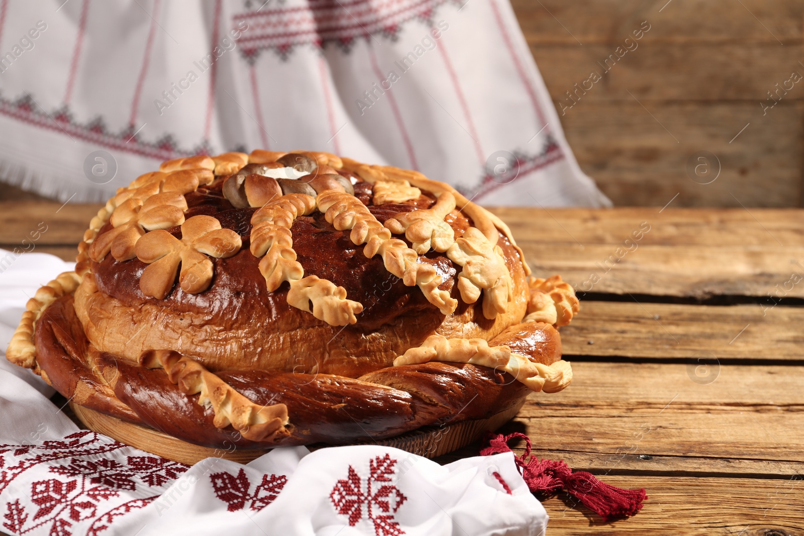 Photo of Korovai with rushnyk on wooden table. Ukrainian bread and salt welcoming tradition
