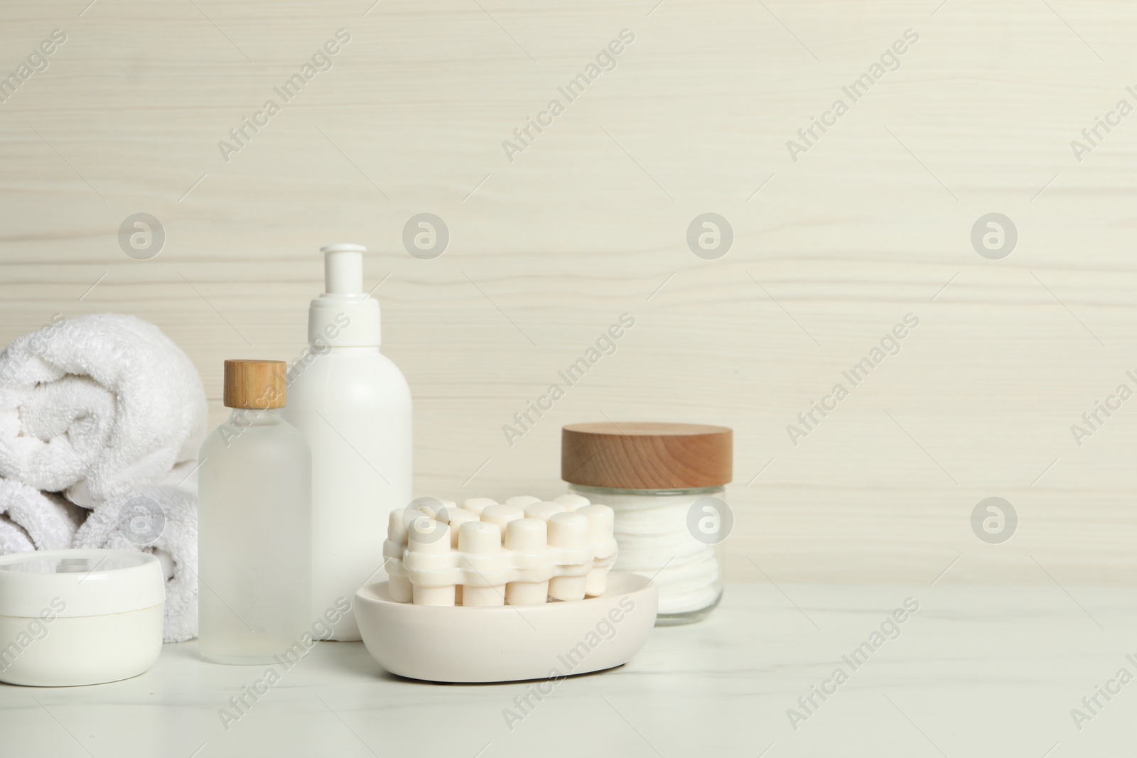 Photo of Different bath accessories and personal care products on white marble table near light wooden wall, space for text