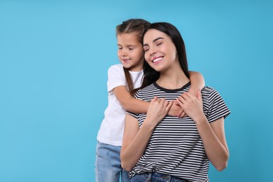 Photo of Happy woman with her cute daughter on light blue background, space for text. Mother's day celebration