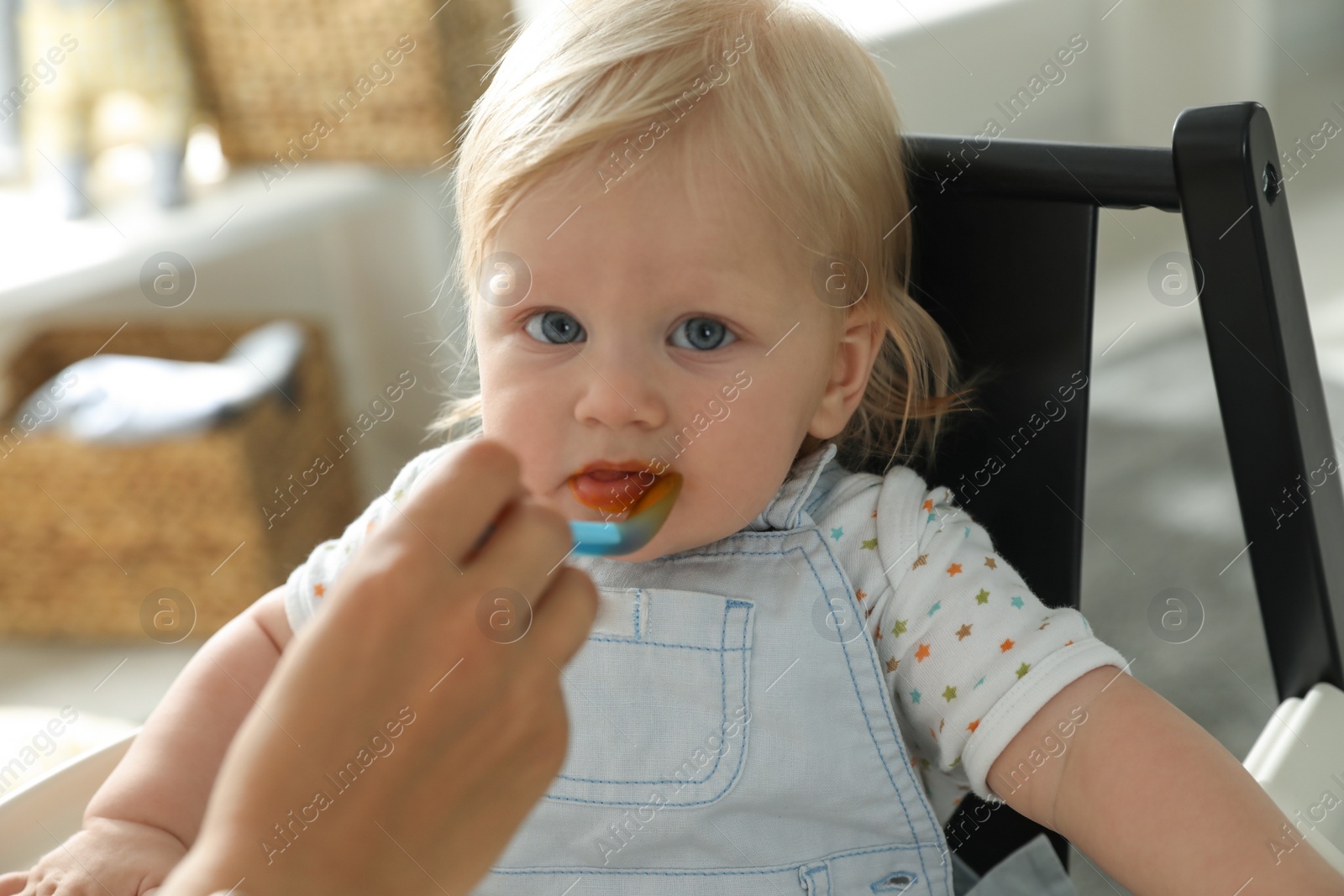 Photo of Mother feeding her cute little baby with healthy food at home