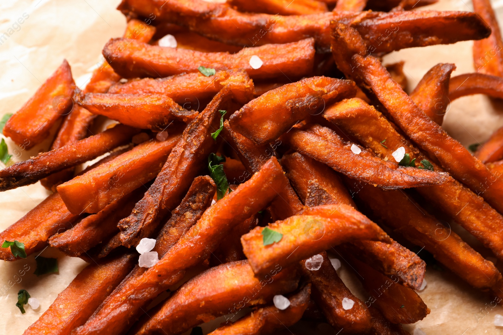 Photo of Delicious sweet potato fries on parchment paper, closeup