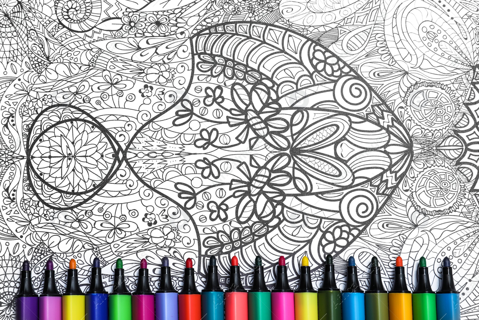 Photo of Felt tip pens on antistress coloring page, top view