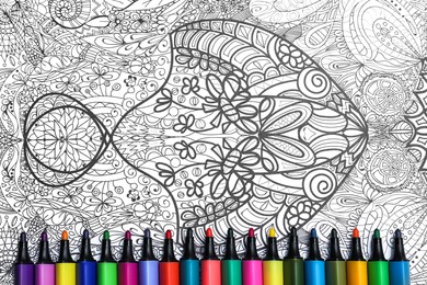 Photo of Felt tip pens on antistress coloring page, top view