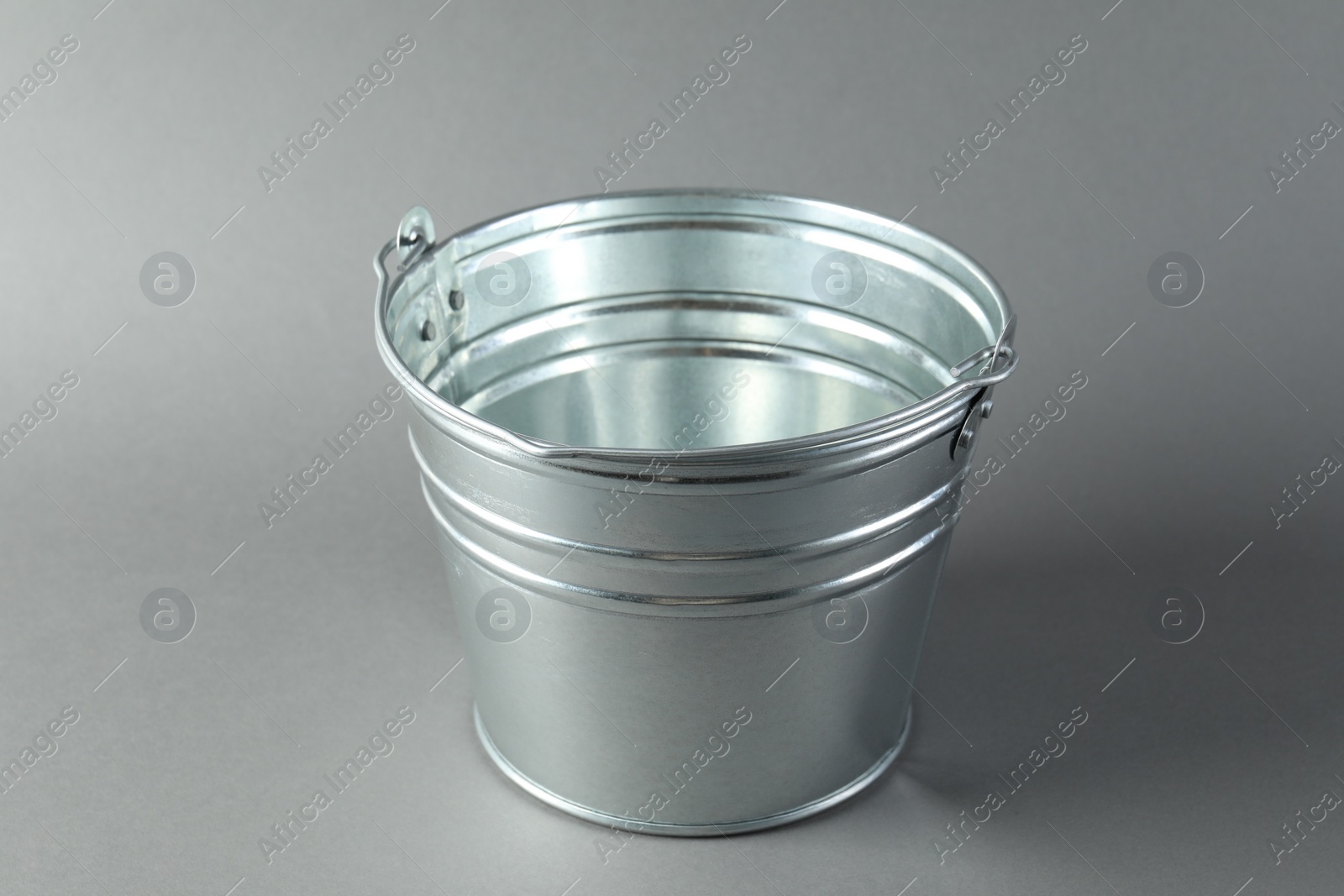 Photo of One shiny metal bucket on light grey background