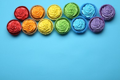 Photo of Many tasty cupcakes with bright cream on light blue background, flat lay. Space for text