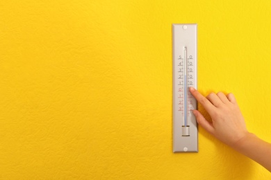 Woman with weather thermometer on yellow background, closeup. Space for text