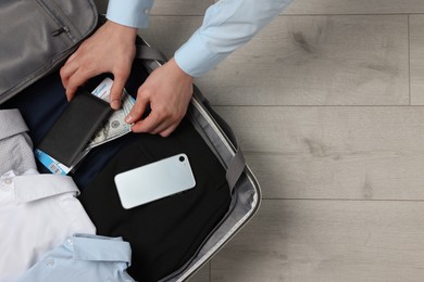 Photo of Man packing suitcase on wooden floor, top view with space for text. Business trip planning