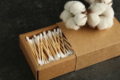 Photo of Cotton swabs and flowers on black table, closeup