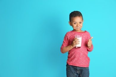 Photo of Adorable African-American boy with glass of milk on color background