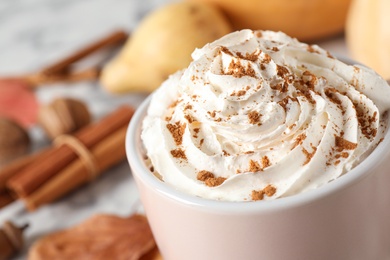 Cup with tasty pumpkin spice latte on table, closeup