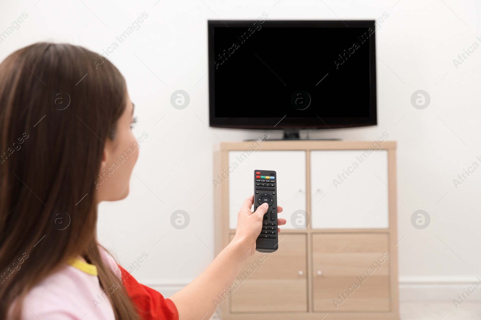 Photo of Woman changing TV channel with remote control in living room. Space for text