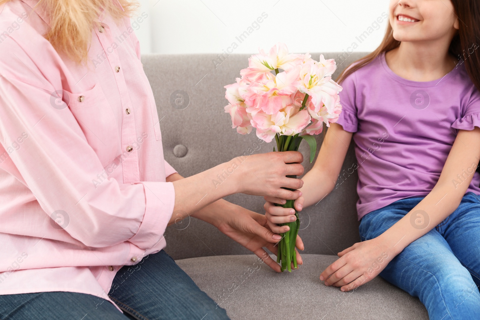 Photo of Little daughter congratulating her mature mom at home, closeup. Happy Mother's Day