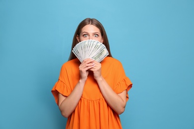 Portrait of happy lottery winner with money fan on light blue background