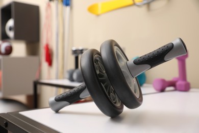 Abdominal wheel on white table in room with other sports equipment