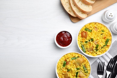 Photo of Delicious rice pilaf with meat served on white wooden table, flat lay. Space for text