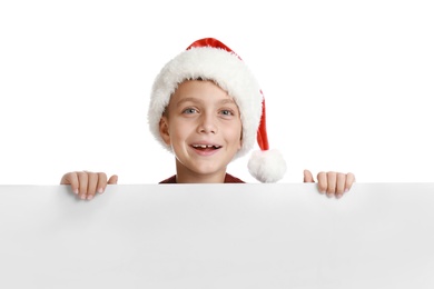 Photo of Happy child in Santa hat peeping out of blank banner on white background. Christmas celebration