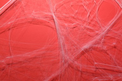 Photo of Creepy white cobweb hanging on red background