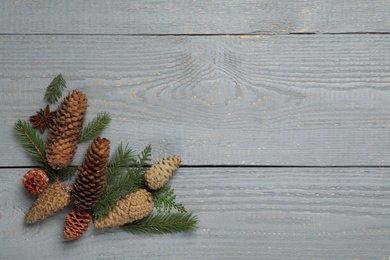 Photo of Flat lay composition with pinecones on grey wooden table, space for text