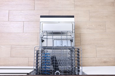 Open clean empty dishwasher in kitchen, top view