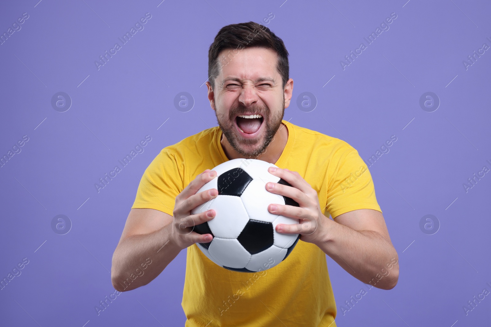 Photo of Emotional sports fan with ball on purple background