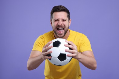 Photo of Emotional sports fan with ball on purple background