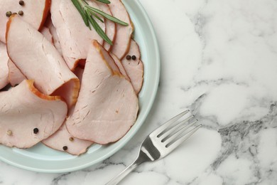 Delicious cut ham with rosemary and peppercorns served on white marble table, flat lay. Space for text