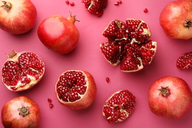 Photo of Whole and cut fresh pomegranates on pink background, flat lay