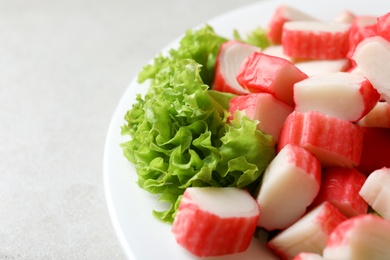 Photo of Cut crab sticks and lettuce on light table, closeup