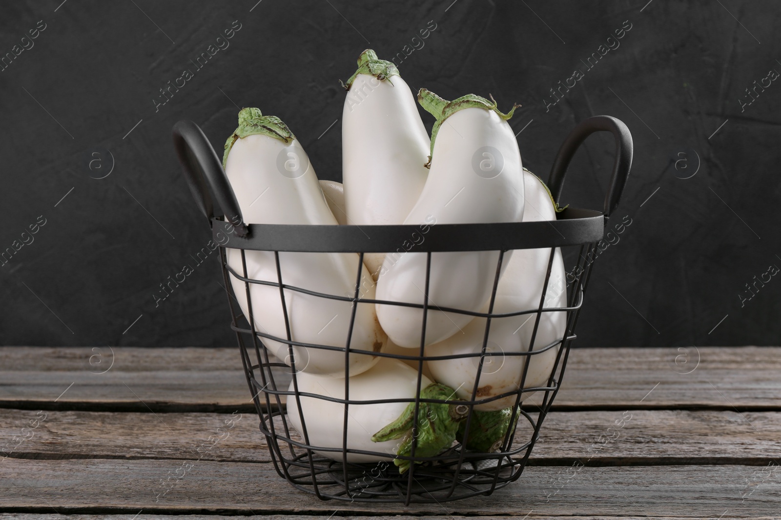 Photo of Fresh white eggplants in metal basket on wooden table