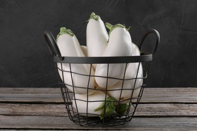 Fresh white eggplants in metal basket on wooden table